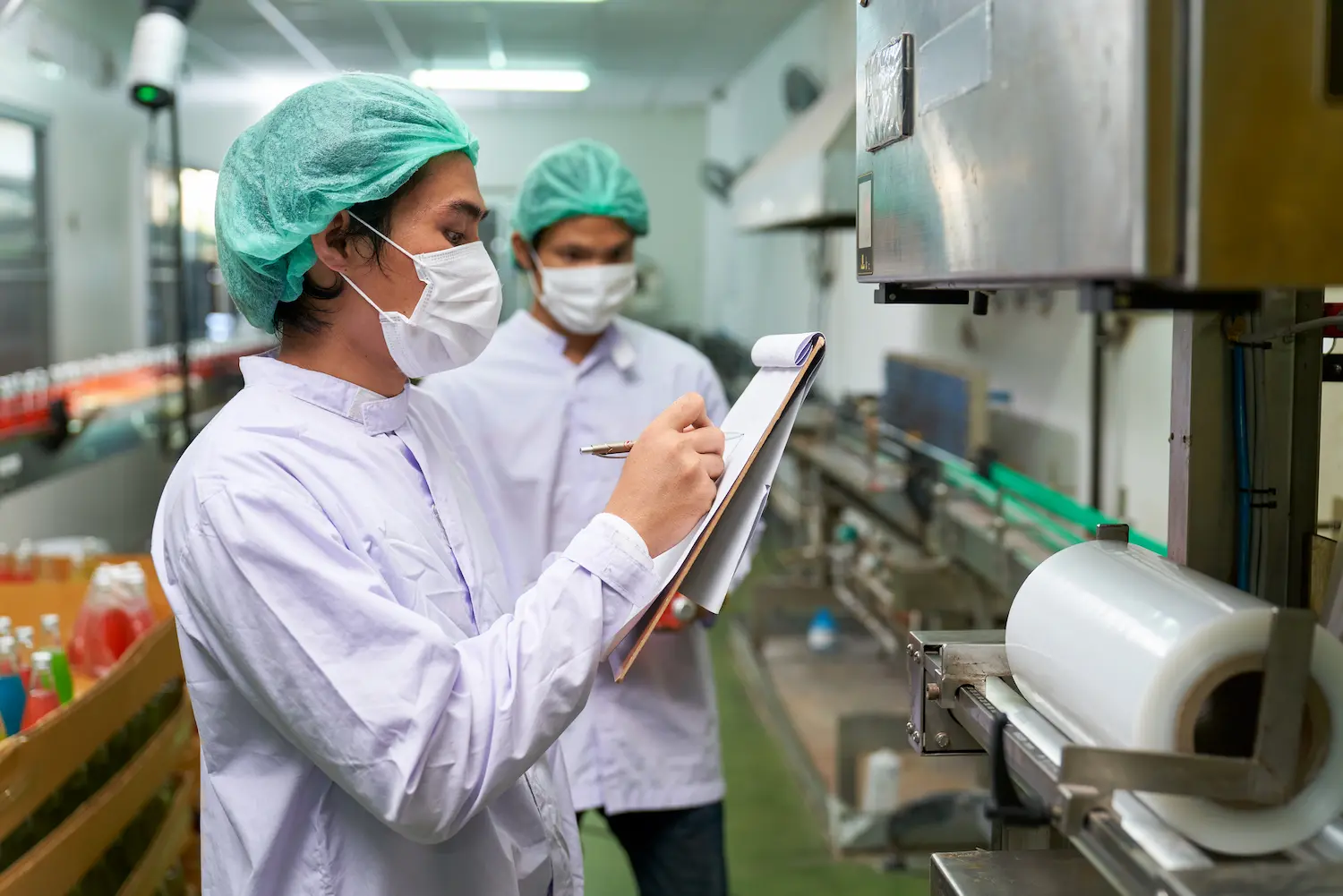 Two food service workers in PPE inspecting some equipment in a kitchen for training