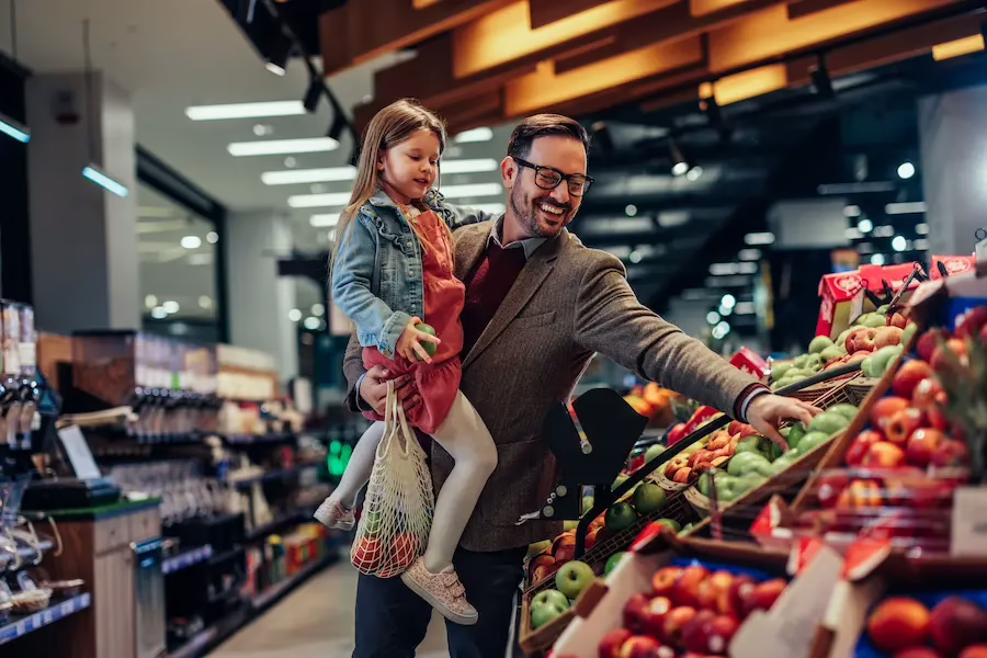 A man shopping for apples with his daughter.