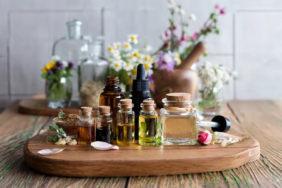 Collection of essential oil bottles and fresh herbs on a wooden board, commonly used as natural rat repellents.