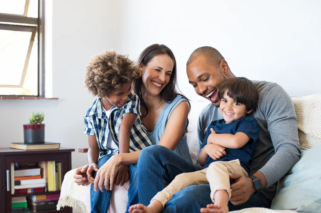 Family having fun on a couch - Keep pests away from your home with Bug Out in NC