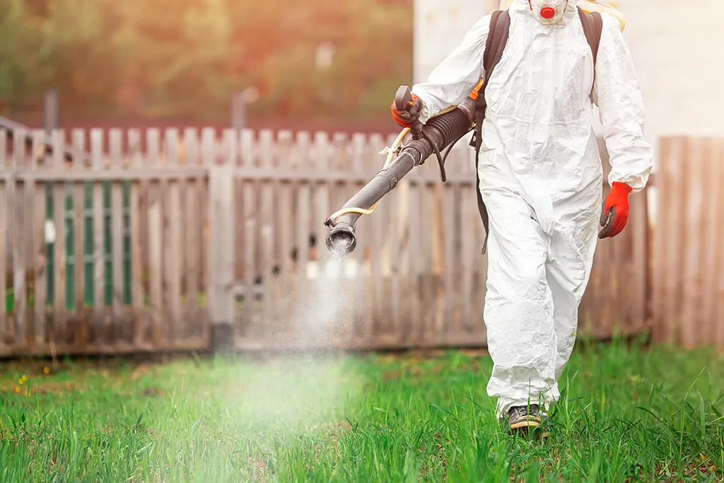 Pest control expert spraying mosquito treatment in an open field