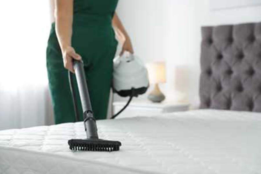 Person steam cleaning a mattress