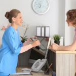 A nurse checking a patient into a medical facility at the front desk.