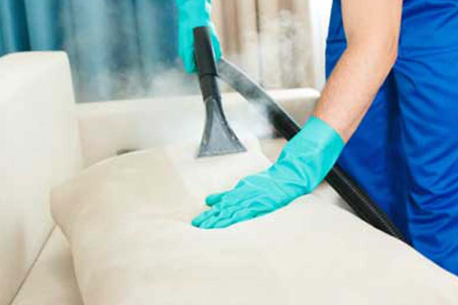 Gloved hands steam cleaning couch cushions
