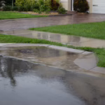 A residential sidewalk in front of a home is flooded with water.