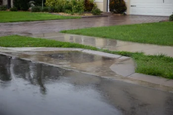 A residential sidewalk in front of a home is flooded with water.